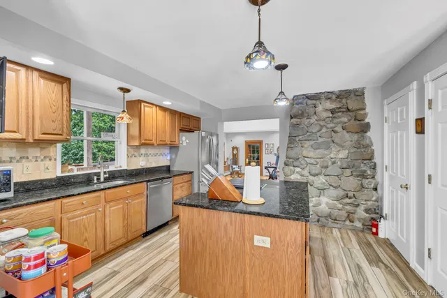 a kitchen with stainless steel appliances granite countertop a refrigerator a sink dishwasher a stove and white countertops with wooden floor