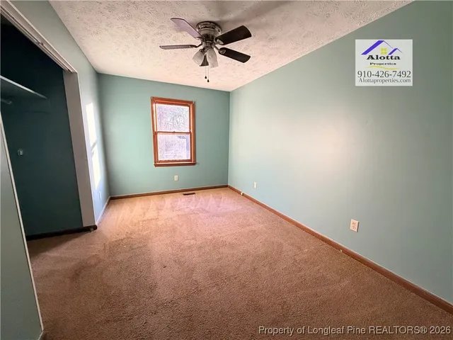 an empty room with windows and ceiling fan