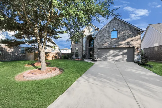 a front view of a house with a yard and a tree