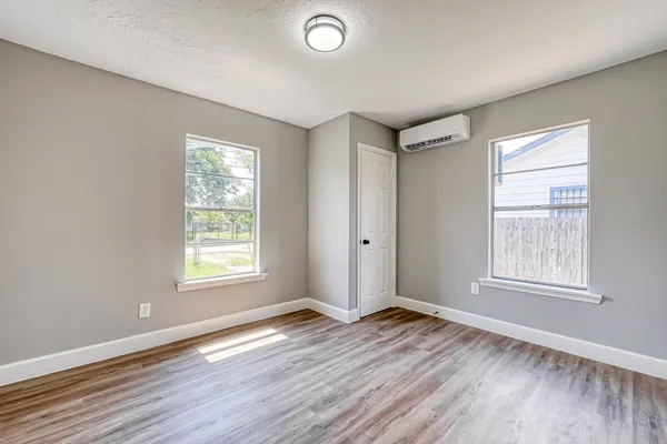 a view of empty room with wooden floor and fan