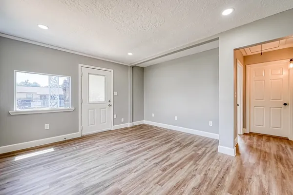 a view of an empty room with wooden floor and a window