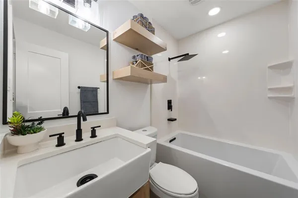 a bathroom with a sink a toilet a mirror and shower