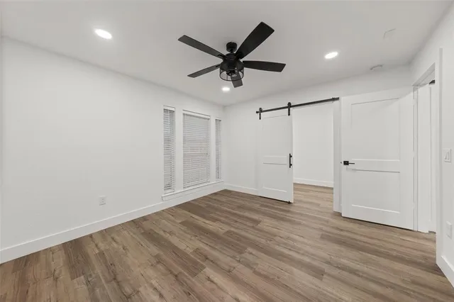 a view of an empty room with wooden floor and a ceiling fan