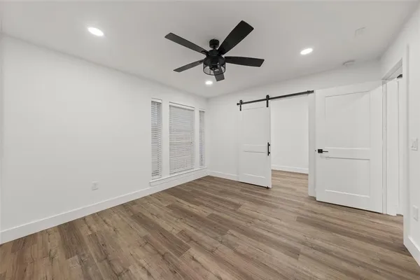 a view of an empty room with wooden floor and a ceiling fan