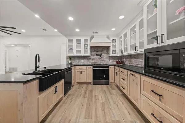 a kitchen with stainless steel appliances granite countertop a sink a stove top oven and white cabinets