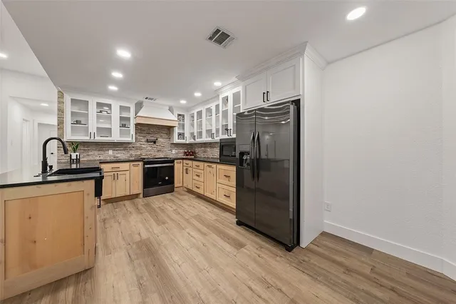 a kitchen with stainless steel appliances granite countertop a refrigerator a sink dishwasher a stove and white countertops with wooden floor