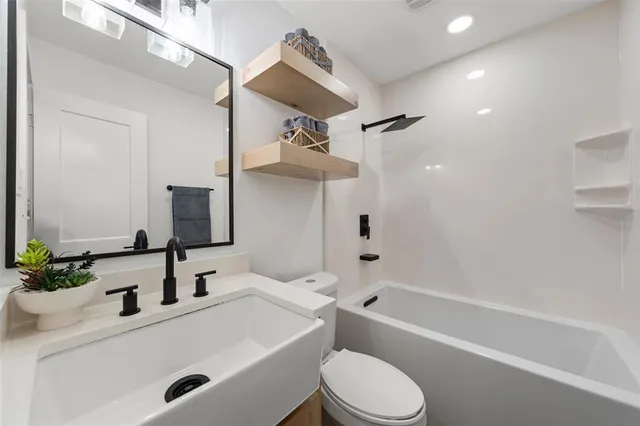 a bathroom with a sink a toilet a mirror and shower