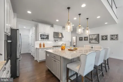 a kitchen with stainless steel appliances granite countertop a table chairs and a refrigerator