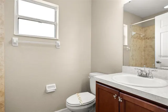 a bathroom with a granite countertop sink toilet a mirror and a window
