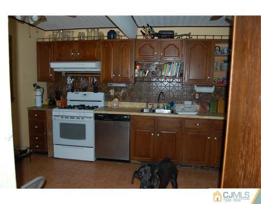23 Barton Road Old Bridge, NJ 08857 - Photo 4 of 7 a kitchen with stainless steel appliances granite countertop a stove a sink and a microwave
