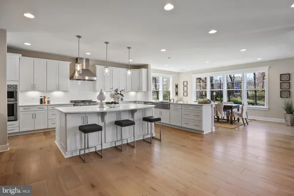 a kitchen with stainless steel appliances kitchen island granite countertop wooden floors and white cabinets