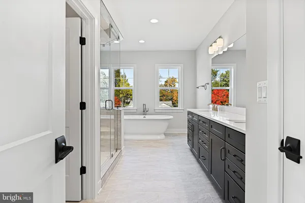 a large white kitchen with a refrigerator a sink dishwasher and a large mirror next to a window