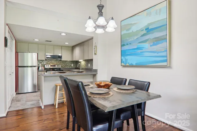 a kitchen with stainless steel appliances granite countertop a dining table chairs and a refrigerator