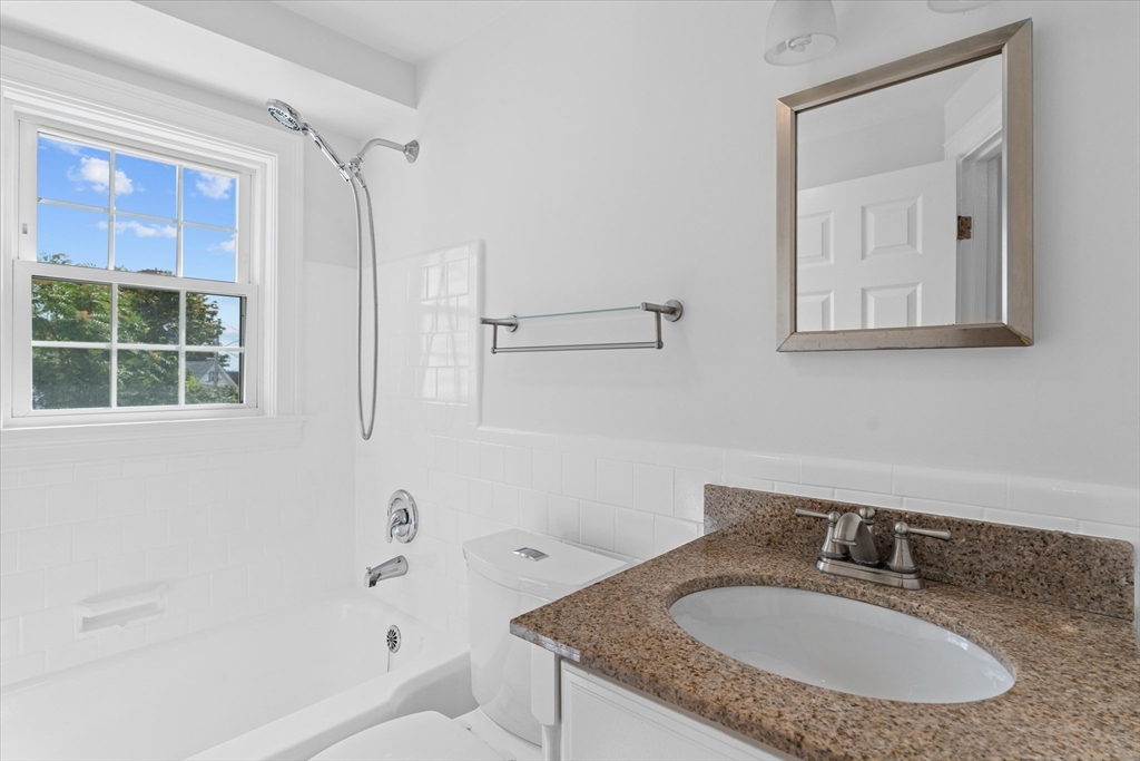 91 Prentice Street Waltham, MA 02451 - Photo 17 of 38 a bathroom with a granite countertop sink a window and a mirror