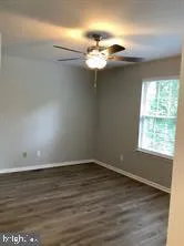 an empty room with wooden floor fan and windows