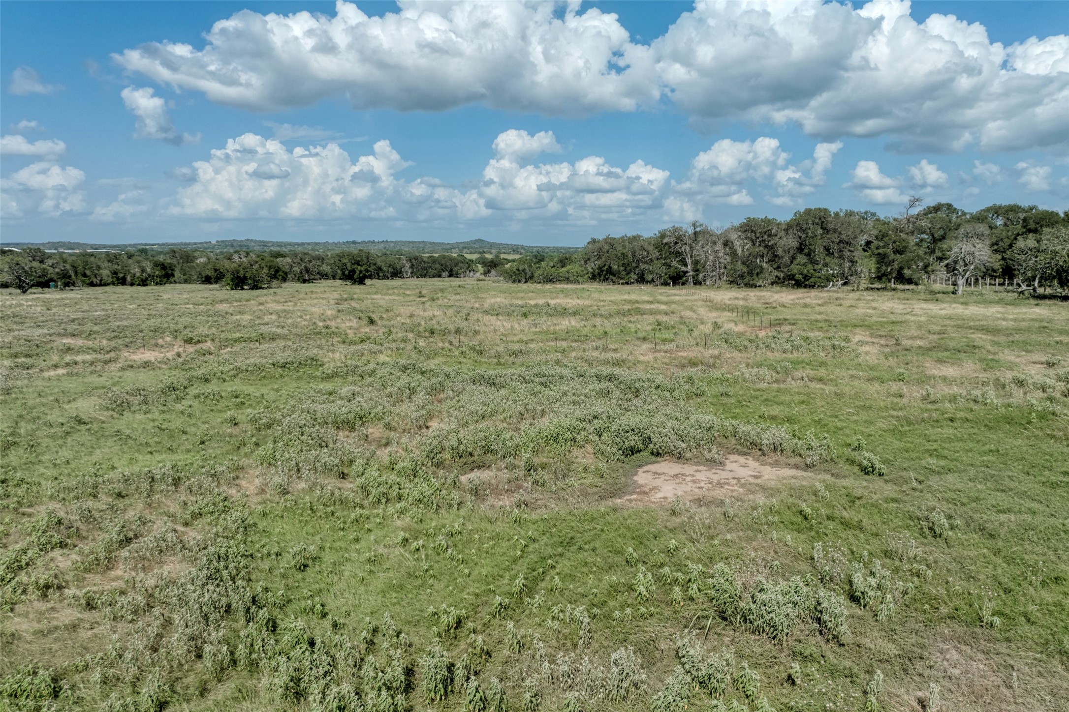 5309 Tenney Creek Road Luling, TX 78648 - Photo 7 of 23 Vast, open acreage offering a private rural setting with distant tree lines under a dynamic sky.