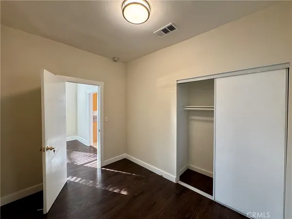 an empty room with wooden floor door and closet