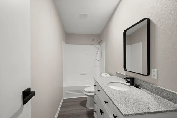 a bathroom with a granite countertop sink toilet and mirror