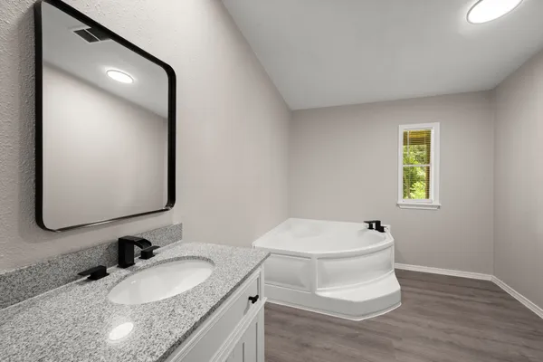 a bathroom with a granite countertop toilet sink and mirror