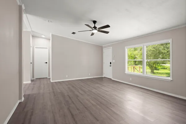 a view of an empty room with wooden floor and a window