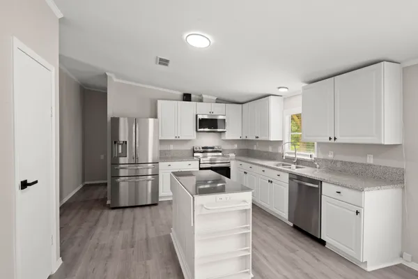 a kitchen with cabinets stainless steel appliances a sink and wooden floor