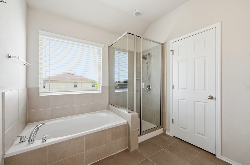209 Noddy Road Buda, TX 78610 - Photo 20 of 27 Tiled flooring and a separate walk-in shower elevate this functional bathroom layout.