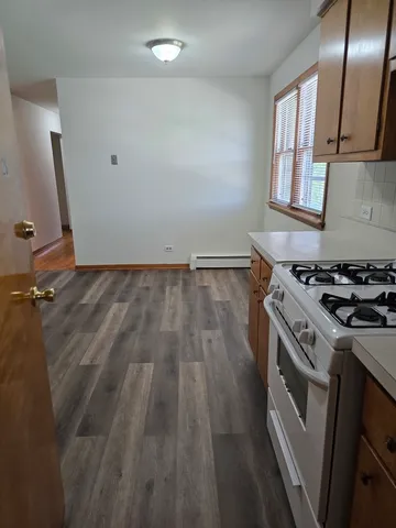 a kitchen with a stove wooden floor and a window