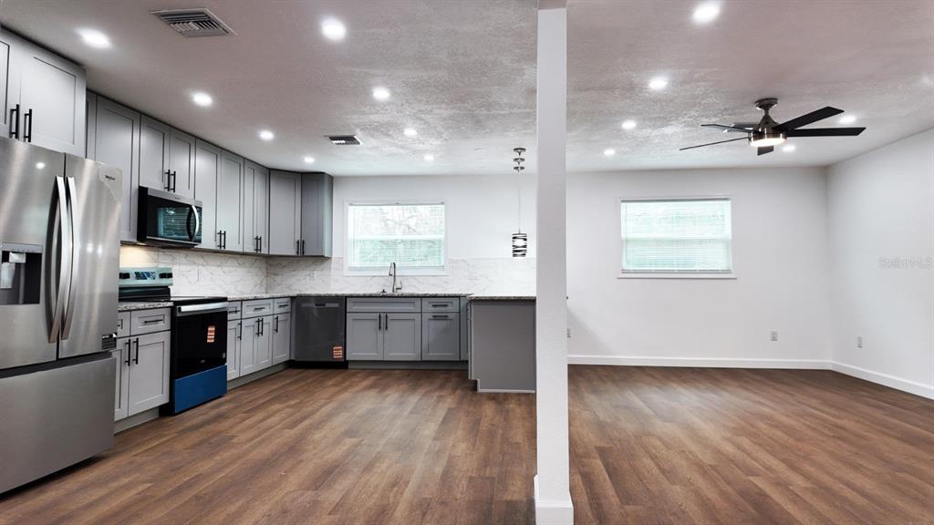 2607 Northeast 140th Street Citra, FL 32113 - Photo 10 of 36 a large kitchen with stainless steel appliances granite countertop a stove a sink dishwasher and a refrigerator with wooden floor
