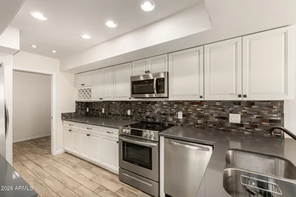 a kitchen with granite countertop a sink stainless steel appliances and cabinets
