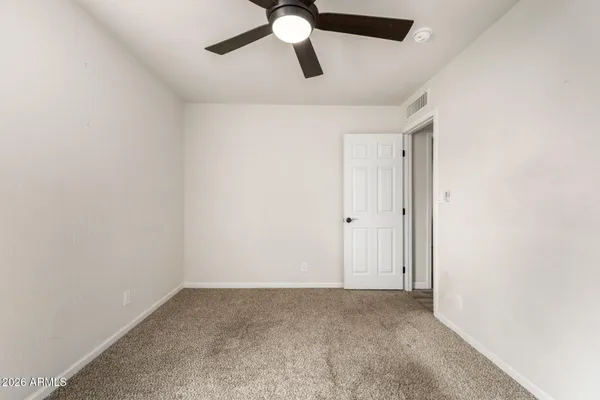 a view of an empty room with wooden floor and ceiling fan