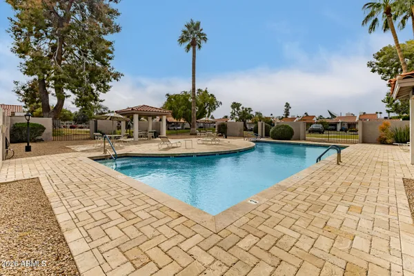 a view of a swimming pool with a table and chairs under an umbrella