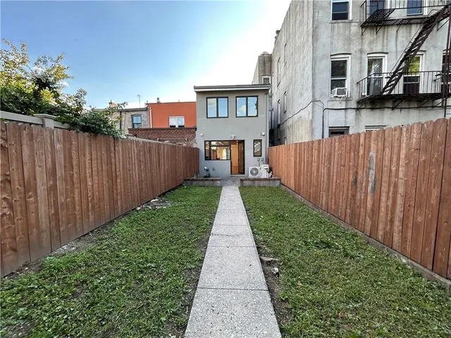 a view of a yard with plants and a bench