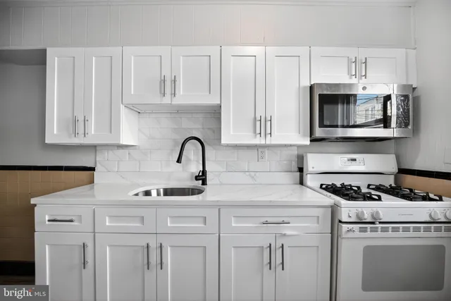 a kitchen with white cabinets and appliances