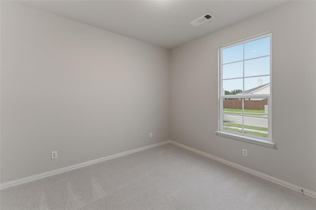 1329 Frio Drive Springtown, TX 76082 - Photo 6 of 25 Neutral-toned room featuring a large window with grid pattern, light gray carpeting, matching baseboards, and a ceiling-mounted light fixture