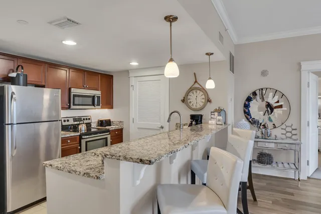 a kitchen with refrigerator a stove a dining table and chairs with wooden floor