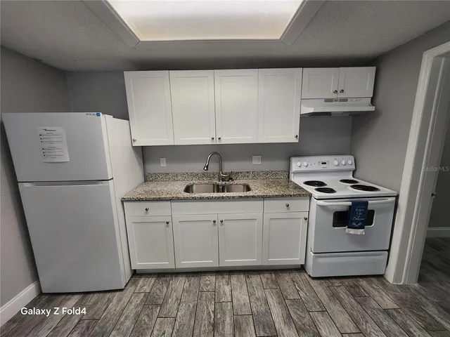 a kitchen with granite countertop white cabinets and white appliances