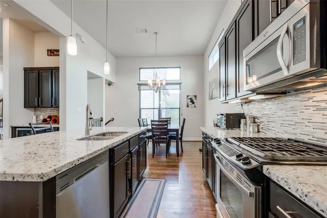 a kitchen with stainless steel appliances granite countertop a table chairs refrigerator and microwave