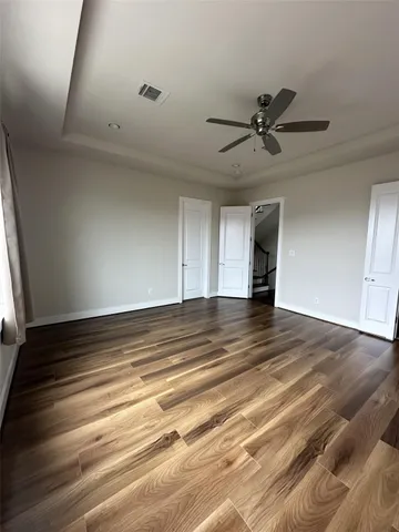 an empty room with wooden floor fan and windows