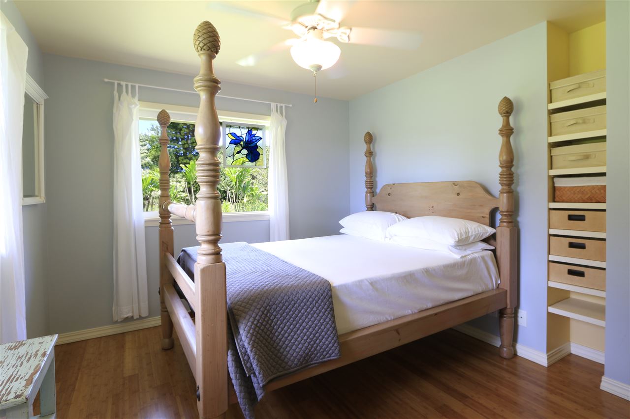 2736 Kaupakalua Road Haiku, HI 96708 - Photo 28 of 30 a bedroom with a bed and a chandelier