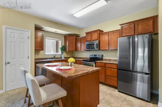a kitchen with stainless steel appliances kitchen island granite countertop a refrigerator and a stove top oven