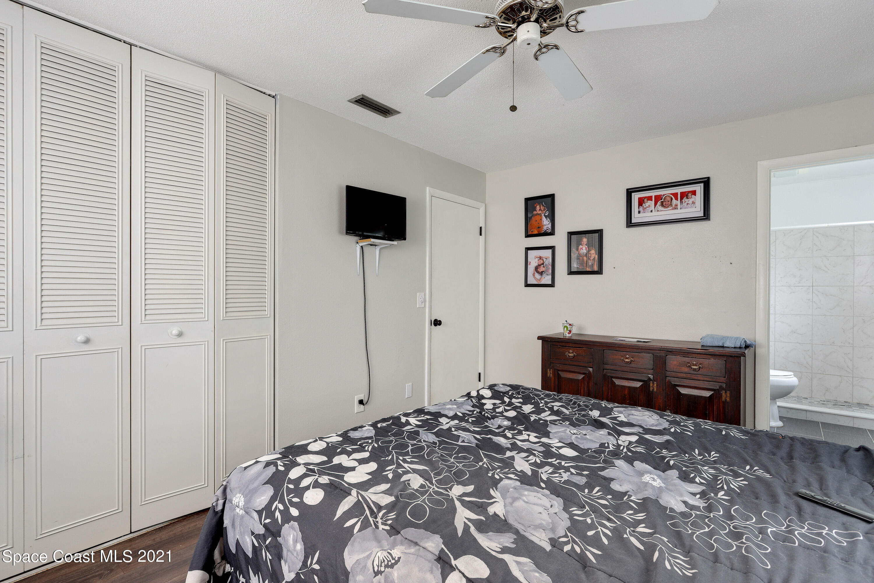 2710 King Richard Road Melbourne, FL 32935 - Photo 12 of 17 a bedroom with a bed and a chandelier