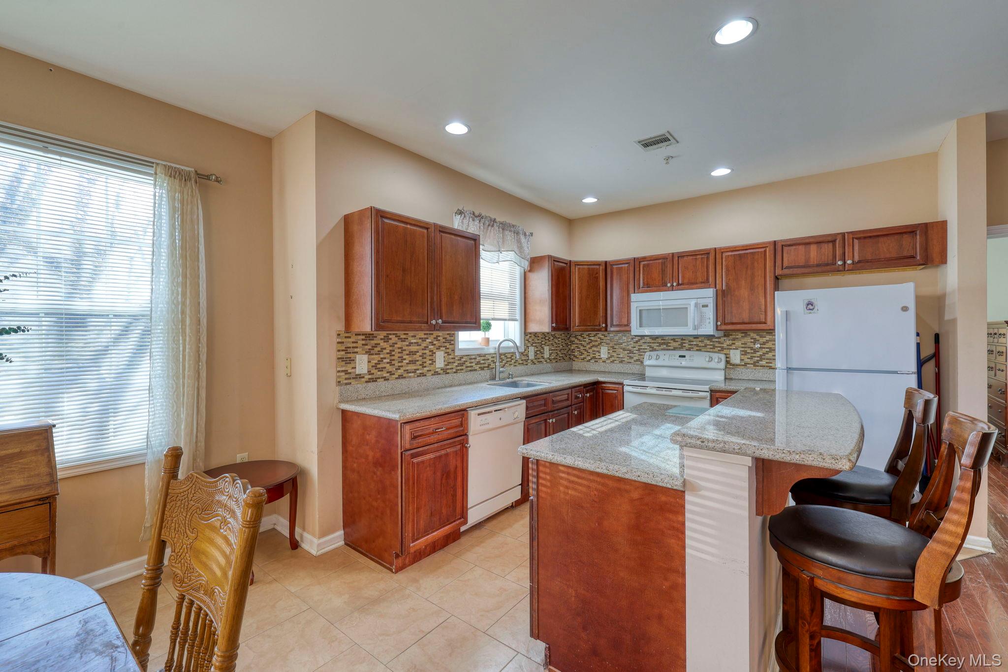 927 Tower Ridge Circle Middletown, NY 10941 - Photo 16 of 36 Kitchen featuring light stone countertops, a kitchen bar, white appliances, backsplash, and a center island
