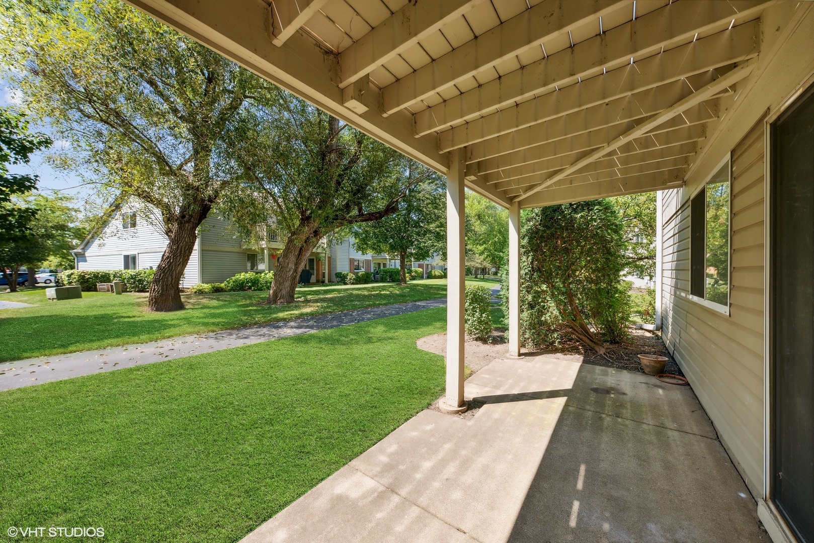 1406 Aldgate Court, Unit D1 Wheeling, IL 60090 - Photo 15 of 16 a porch with a table and chairs next to a yard