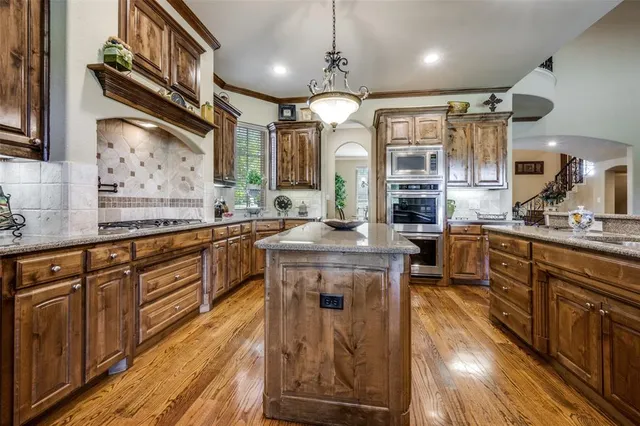 a kitchen with stainless steel appliances granite countertop a sink a stove and a wooden floors