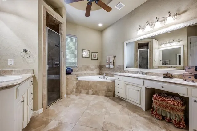 a large bathroom with a granite countertop double vanity sink a mirror and a bathtub