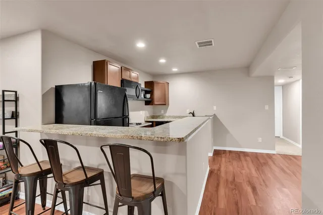 a kitchen with stainless steel appliances granite countertop a table chairs sink and wooden floor