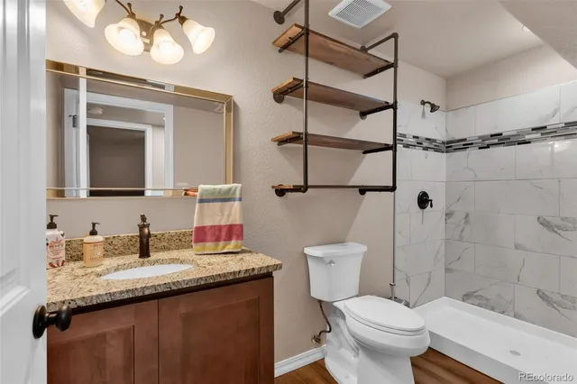 a bathroom with a granite countertop sink toilet and shower