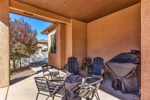 a patio with table and chairs and potted plants