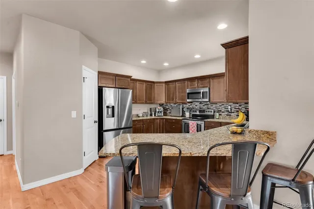 a kitchen with stainless steel appliances granite countertop a refrigerator and a stove top oven