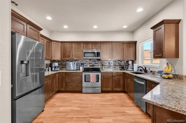 a kitchen with stainless steel appliances granite countertop a refrigerator sink and stove